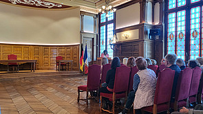 Rathaussaal der Stadt Hénin-Beaumont mit Stühlen und Personen, die der Rede der Beigeordneten zuhören